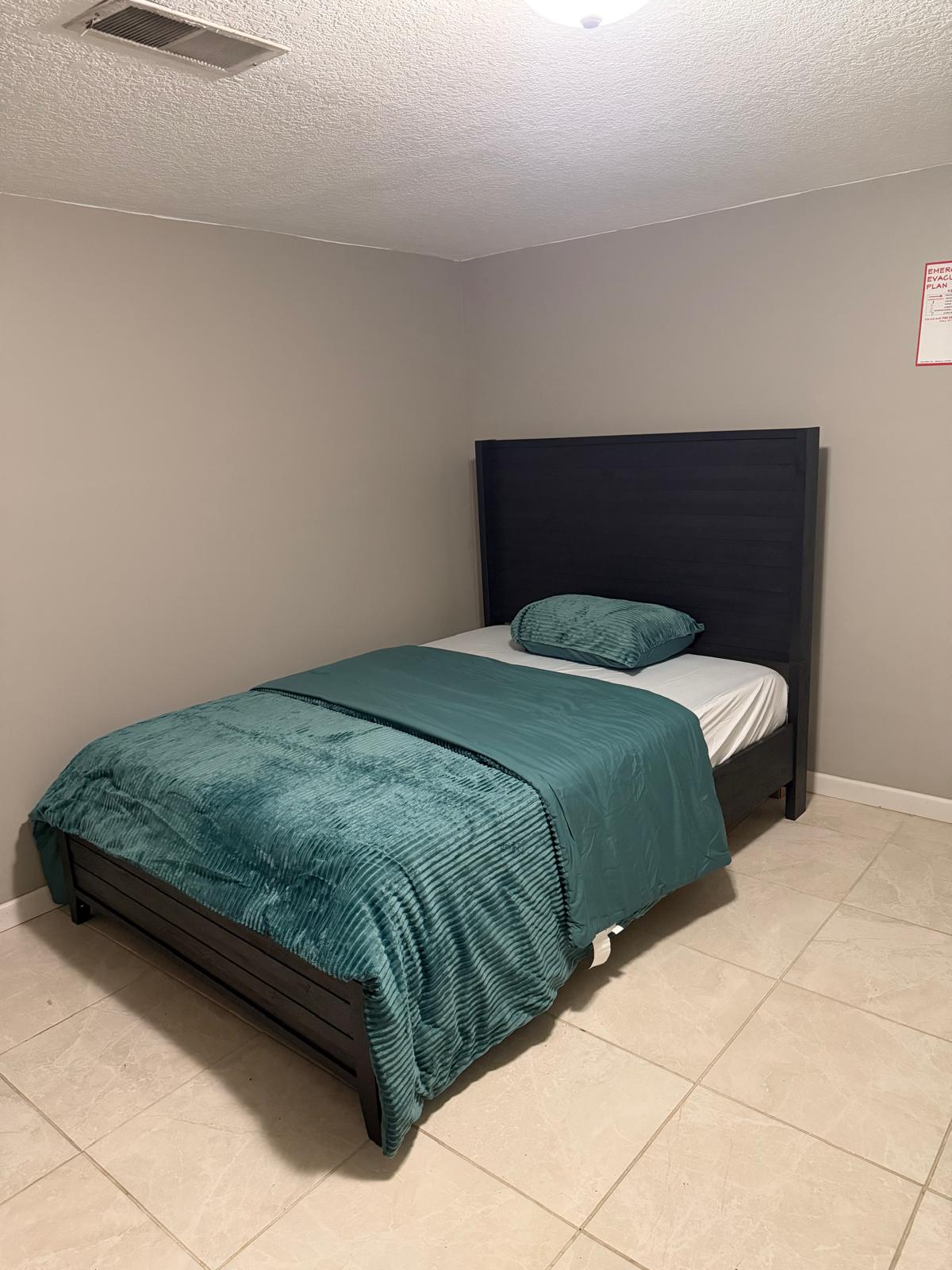 Furnished private bedroom with teal bedding and a dark headboard