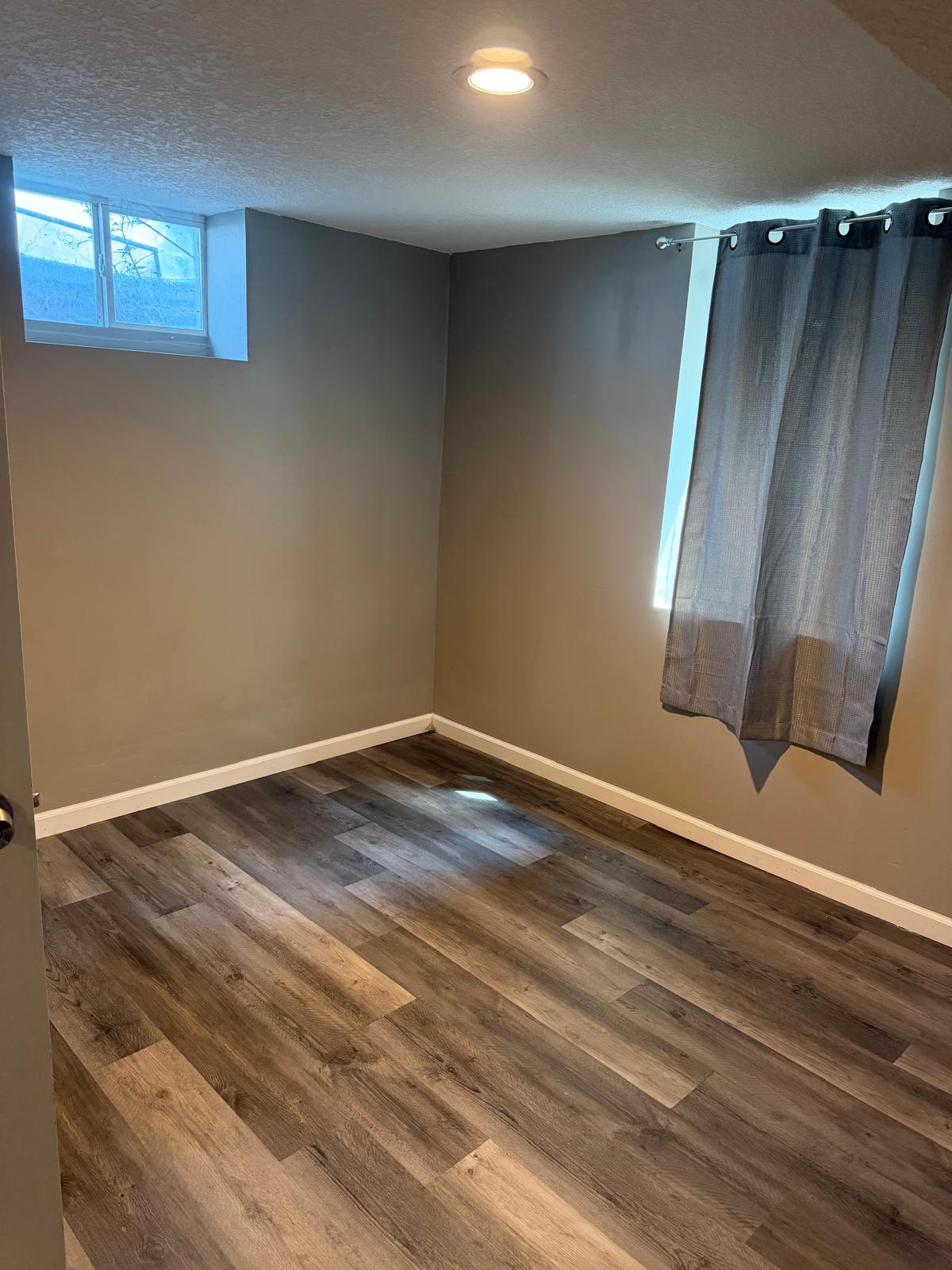 Clean private room with wood-look flooring and windows